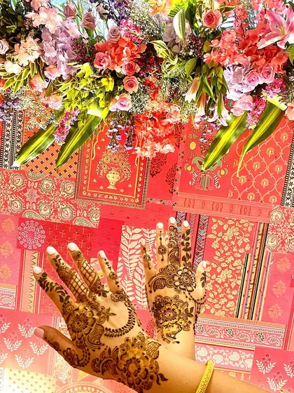A beautiful shot of hands with fresh henna against a festive, floral backdrop. This captures the vibrant atmosphere of a mehndi party.