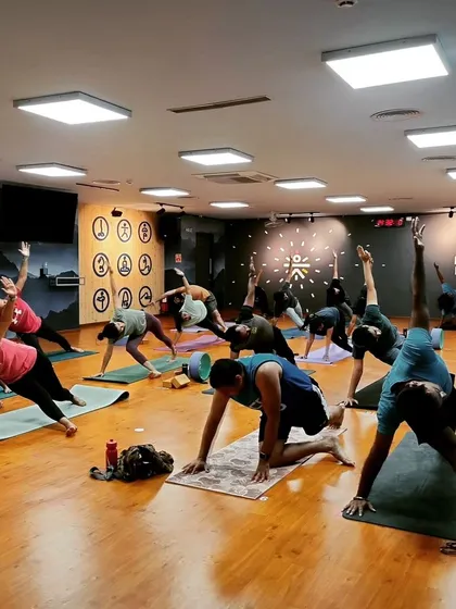 The energy in our group classes is everything. Here you can see a full studio of students moving together, each on their own journey but sharing a collective focus and strength in a Vasisthasana (Side Plank) variation.