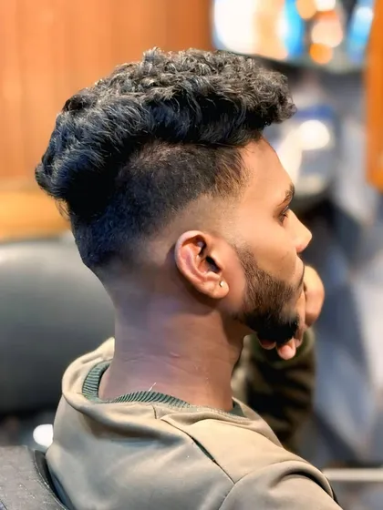 A side view of the curly hair fade, showing the sharp line-up and the contrast between the tight fade and the voluminous curls.