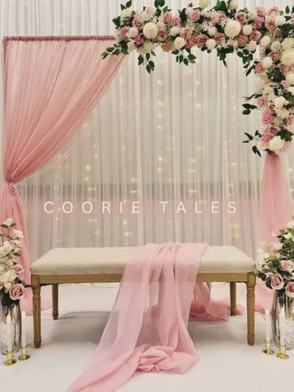 An elegant and timeless decor for an engagement ceremony. This beautiful setup features a soft pink floral arch over a classic bench, with delicate draping and fairy lights creating a romantic and dreamy backdrop.