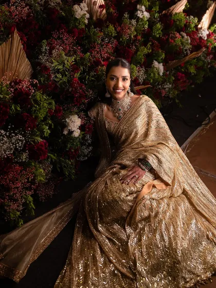 Surrounded by florals, she looks absolutely stunning. The soft glam makeup enhances her features without competing with the dazzling saree.