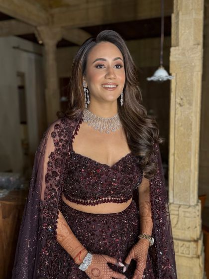 The final look. The bride looks confident and beautiful, with her glamorous makeup perfectly complementing her sparkling deep wine-colored lehenga and diamond jewelry.