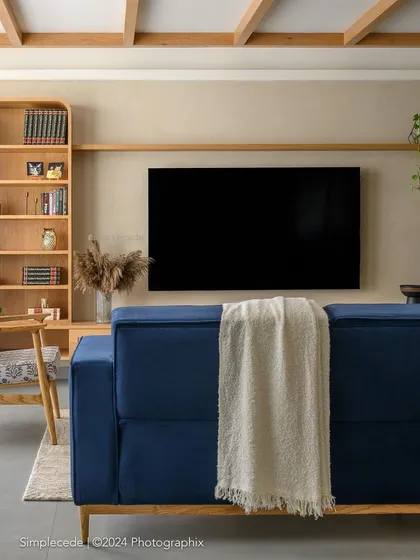 A close-up of the TV space in 'Cover me in Sunshine', showing the curved niche that frames the television and the integrated wooden bookshelf.