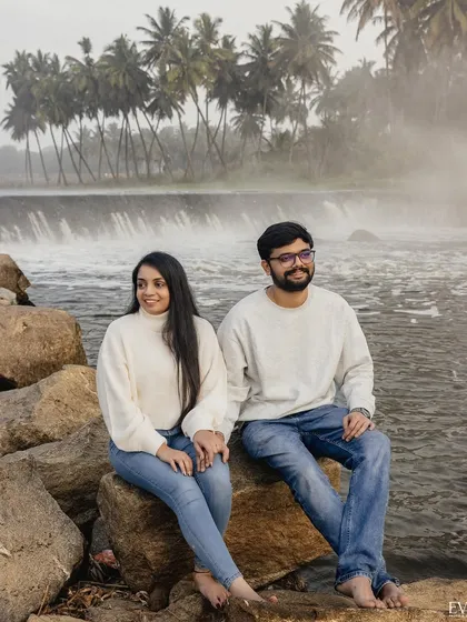 A serene moment for Amrutha and Varun, sitting by a waterfall with palm trees in the background. A perfect example of our relaxed, scenic pre-wedding photography.
