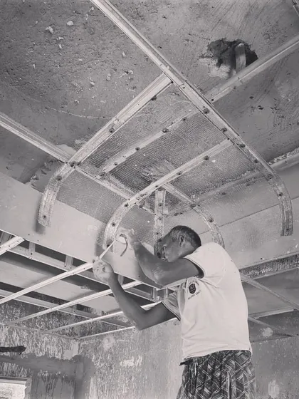 A craftsman installing the framework for a curved ceiling. This image captures the skill required to translate our complex drawings into physical reality.