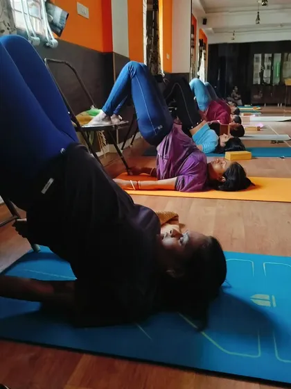 Participants use chairs to practice a variation of Setu Bandhasana (Bridge Pose). This is a fantastic way to strengthen the back and glutes while relieving pressure on the neck and shoulders.