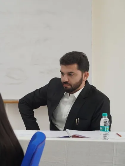 A candid shot of me listening intently to a student's argument during a moot court competition. My focus is on identifying strengths and areas for improvement in their legal reasoning and presentation.