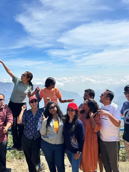 A candid group photo on a mountain top, with clouds rolling in below.
