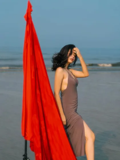 The wind catching the red fabric creates a sense of movement and drama, contrasting beautifully with the calm sea in the background.