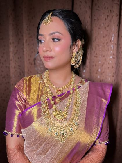 A side profile of Archana, showing how the soft makeup and elegant updo complement her stunning Kanjeevaram saree.