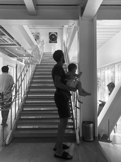 A visitor with a small child enjoys the view from the main staircase at the Museum of Art and Photography (MAP). The building's open and light-filled circulation spaces are designed to be welcoming for everyone.