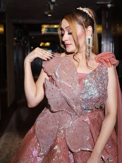 A close-up of the large, artistic floral detail on the shoulder of the rose-colored tiered gown.