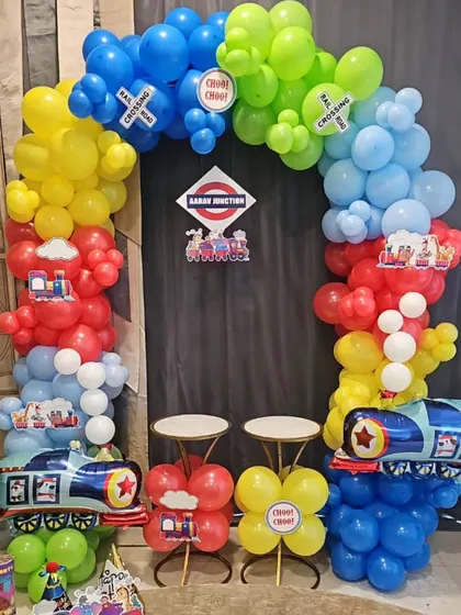 All aboard the birthday express! This train-themed party setup features a balloon arch in primary colors and foil train balloons for a fun photo station.