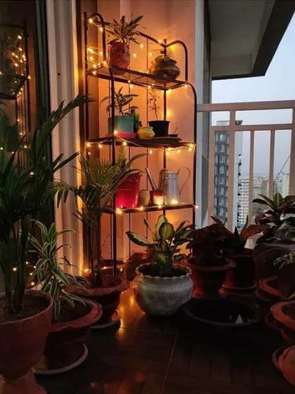 Here is another example of a plant stand illuminated with string lights. It's an easy way to draw attention to your favorite plants and make the space feel cozy and decorated, especially with the city lights in the background.