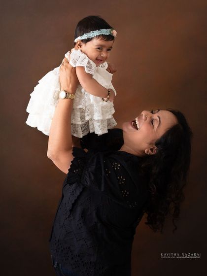A mother's joy is evident as she lifts her eight-month-old daughter into the air. These playful, interactive moments create authentic and happy family portraits.