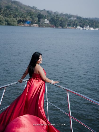 A candid shot of the bride-to-be on a yacht, looking out at the water, her red gown flowing beautifully.