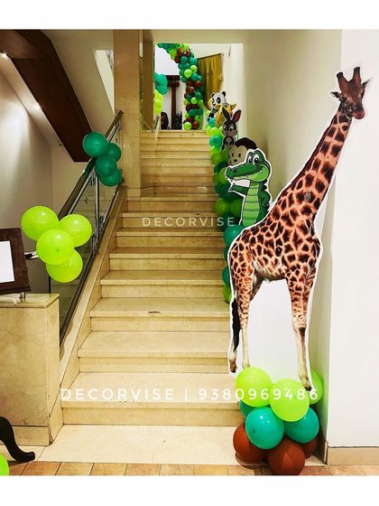 We use the entire event space to build the theme. Here, we decorated a staircase with green balloon clusters and life-sized cutouts of a giraffe and other jungle animals to guide guests through the party.