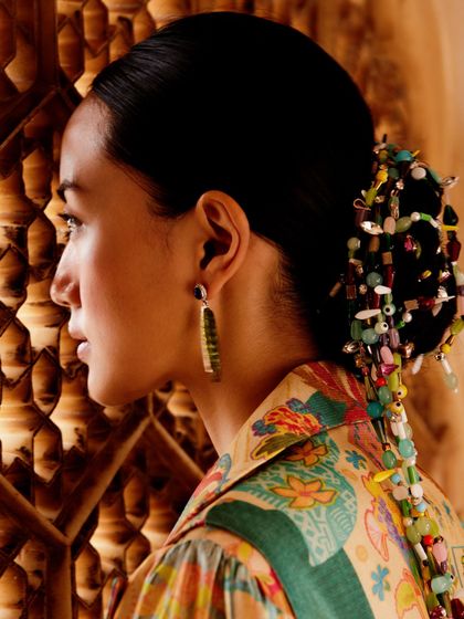 A profile shot highlighting the intricate hair and jewelry styling for the Ani campaign.