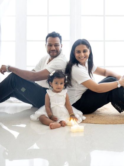 A lovely family portrait celebrating their daughter's first birthday, all dressed in coordinating white outfits for a clean and timeless look.