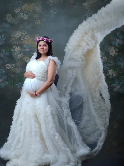 A vision in white. This stunning portrait showcases a designer maternity gown with a dramatic ruffled train, making the mother-to-be look and feel like royalty.
