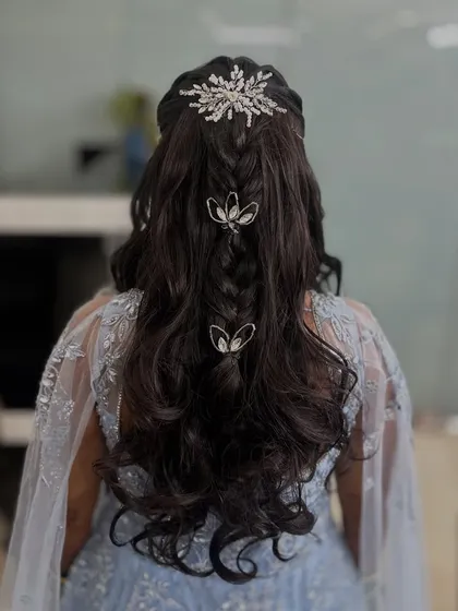 A modern take on a braided hairstyle with open curls, perfect for a gown. The style is decorated with a large crystal clip and smaller butterfly clips.