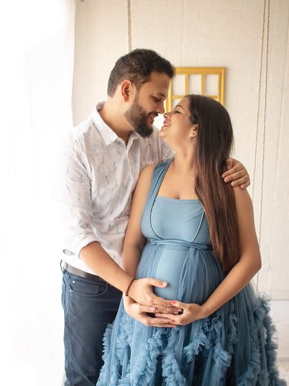 A sweet, candid moment between an expecting couple. The natural light from the window gives this maternity photo a soft and dreamy quality.