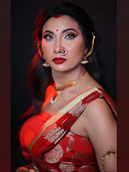 A striking close-up of the goddess look. The dramatic eye makeup, sharp contour, and bold red lip create a fierce and captivating portrait, enhanced by the studio lighting.