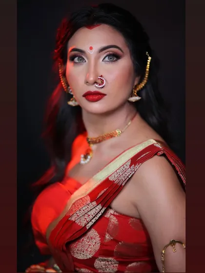 A striking close-up of the goddess look. The dramatic eye makeup, sharp contour, and bold red lip create a fierce and captivating portrait, enhanced by the studio lighting.