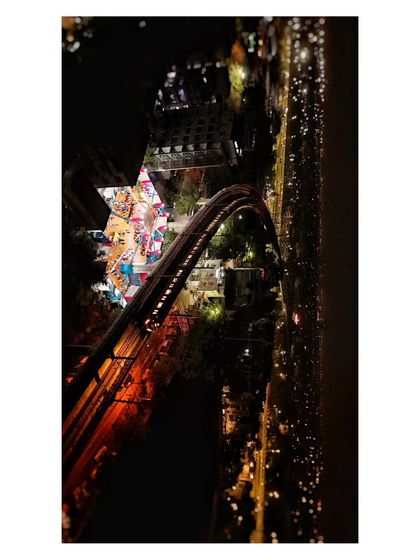 An overhead drone view of a star-shaped event structure illuminated at night, surrounded by city lights.