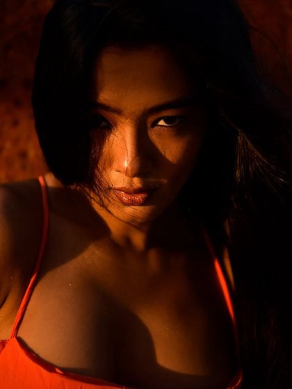 This image was shot using harsh, direct sunlight to create intense shadows and a fiery orange glow. It’s a raw, high-contrast look that feels summery and intense. The shadows carve out the model's features, creating a dramatic and memorable portrait.