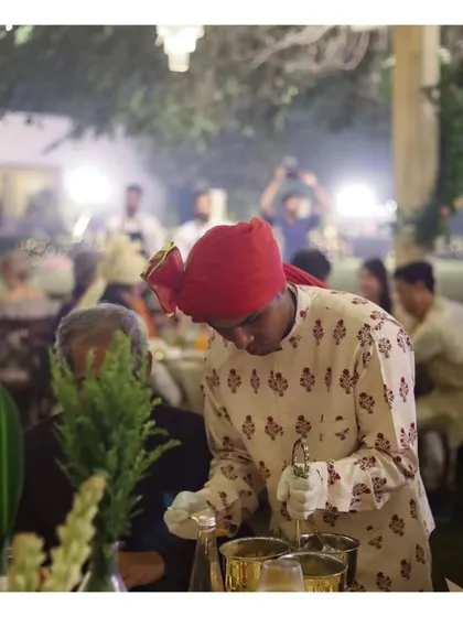 A server in traditional attire carefully serves a dish at a formal Indian dinner. Our team's authentic costuming and professional demeanor are integral to the immersive cultural experiences we provide.