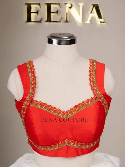 This sleeveless red blouse is perfect for a bold bridal statement. It features a deep V-neckline and is heavily embellished with intricate gold floral zardozi work, creating a rich and luxurious feel.