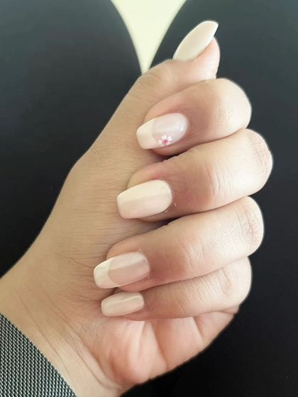 A very subtle and minimalist design on short, natural nails, featuring a sheer nude polish and a single tiny pink rhinestone accent.
