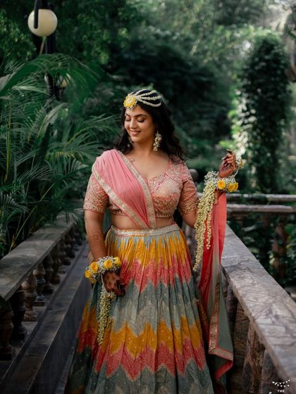 Vibhuti in her colorful Haldi lehenga, adorned with floral jewelry. The makeup is kept light to match the daytime, festive vibe.