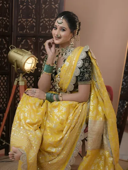 A classic Maharashtrian look featuring a beautiful yellow Paithani saree. The makeup is kept elegant with defined eyes and a traditional nath, perfectly complementing the rich black velvet blouse and green jewellery.