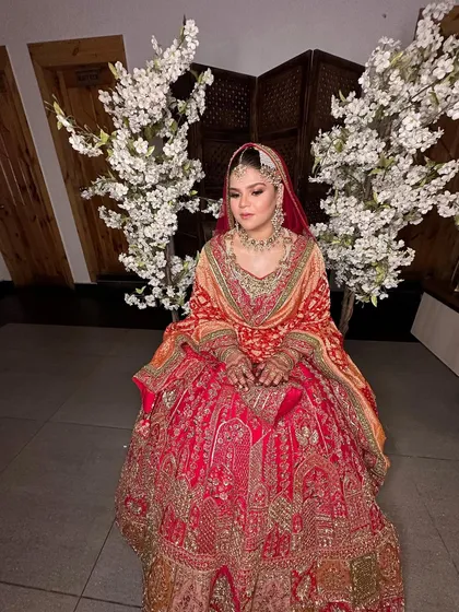 A full view of the bride's stunning attire and makeup. She looks absolutely perfect against the backdrop of white blossoms.