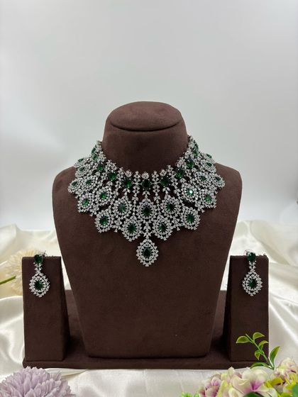 A heavy, silver-plated AD necklace set with a peacock-inspired feather design. This statement piece is available in blue, green, pink, and all-white.