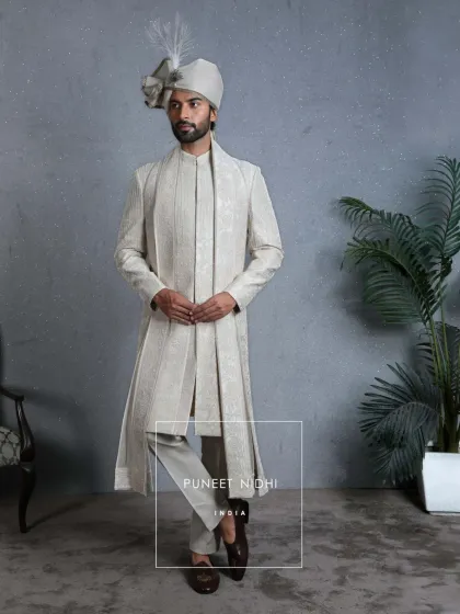 Royalty is not just about grandeur; it’s about grace. This ivory sherwani, with its matching stole and feathered turban, is a complete look that embodies dignity and sophistication.