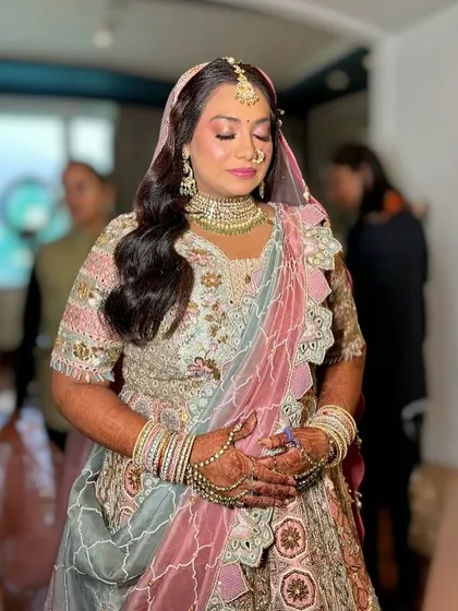 A serene moment captured just after the bride is ready. The soft pink tones in her makeup perfectly match her pastel lehenga.