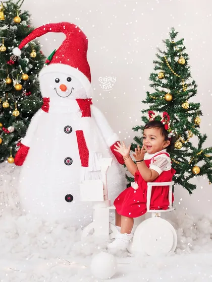 It's snow time! A happy little girl enjoys the winter wonderland scene with her snowman friend.