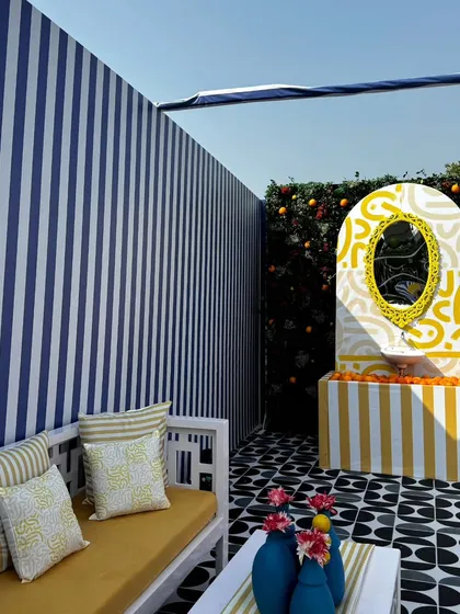 A wide view of the outdoor lounge area, showing the interplay of different patterns. The geometric floor tiles, striped walls, and abstract-patterned vanity create a visually dynamic and artistic space.
