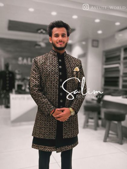 A client wearing a black Indo-Western jacket with a gold brocade pattern, layered over a black velvet kurta. This combination of textures creates a rich and luxurious feel.