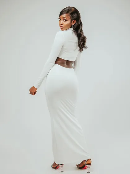 A full-length shot that shows the entire elegant outfit. The turn and look back is a classic fashion pose.