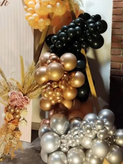 This close-up shows the detail of the organic balloon garland. I used a sophisticated colour palette of chrome gold, silver, black, and peach to complement the rustic brick wall and dried floral elements.