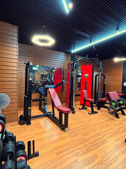 This area is set up for strength training, with multiple machines and a weight rack. We ensure there is enough space around each piece of equipment for safe and effective use. The hexagonal pendant light adds a unique design touch to the space.