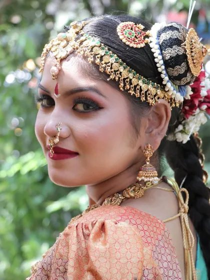 A glance over the shoulder reveals the intricate details of the hair accessories and the flawless finish of the makeup.