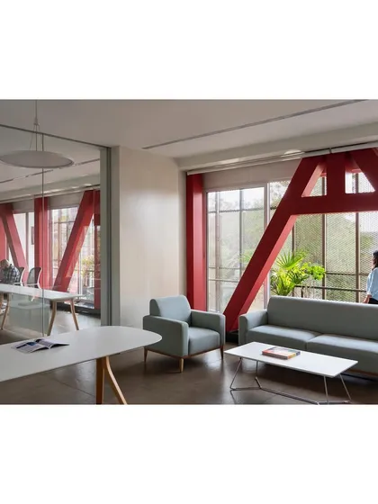 The interior of "Hoverspace" is designed for transparency and flexibility. Glass partitions separate private offices from the open work areas, while the exposed red trusses add industrial character.