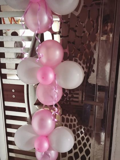 A close-up of a simple balloon pillar made of pink and white balloons with curling ribbons, perfect for doorways or corners.