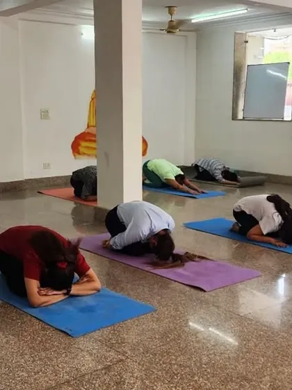 Students practicing Balasana (Child's Pose) during a class at our Noida institute, a moment of rest and introspection.