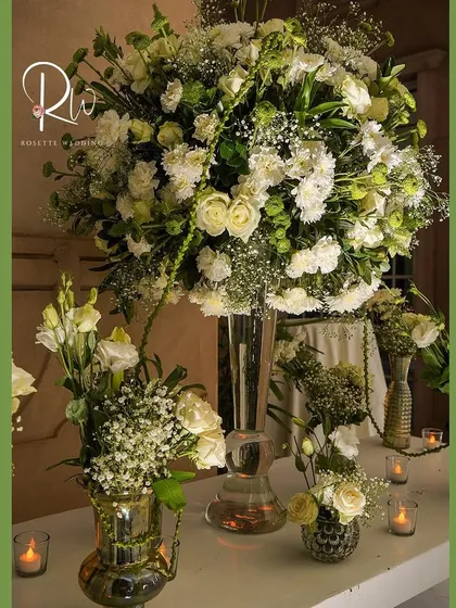 A large centerpiece of white carnations, roses, and baby's breath, surrounded by candles. This is a classic element of my enchanted forest theme.